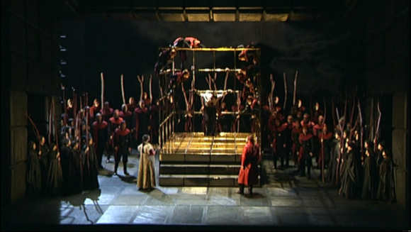 Macbeth (Carlos Álvarez) crucificat, dins la gàbia, en l'escena «Finale» del IV acte.